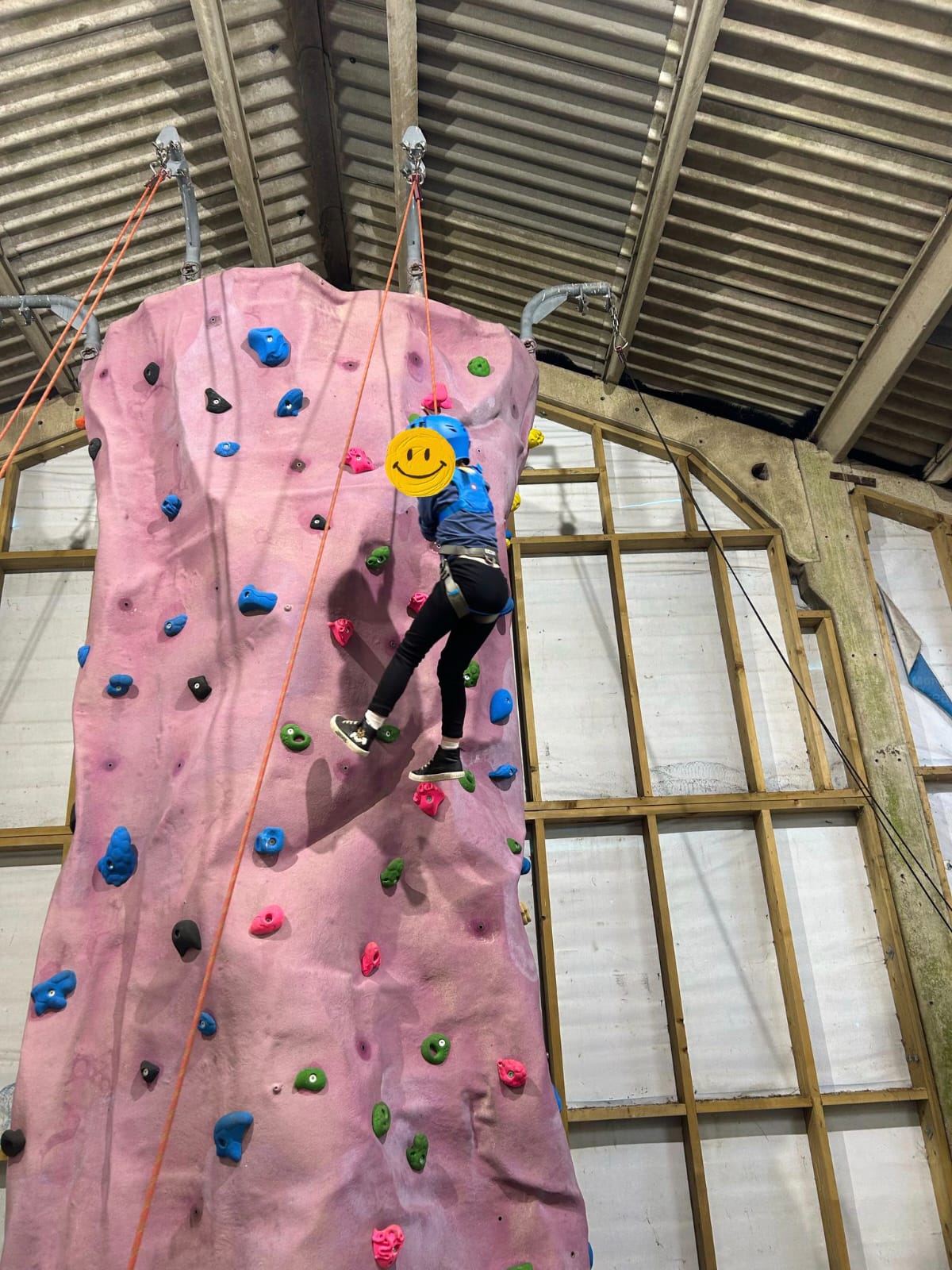 A young child at the top of an indoor climbing wall