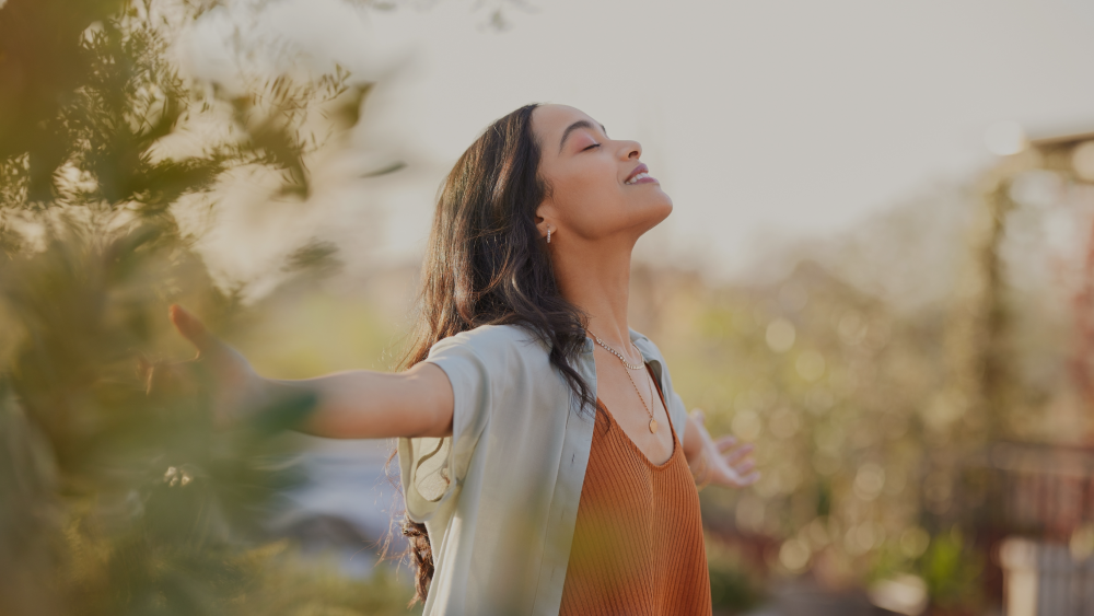 Young lady holding her arms out to the sun with her eyes closed