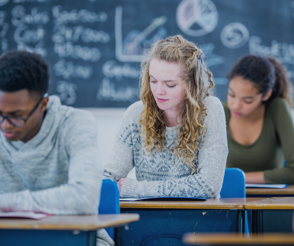 Group of teenagers sitting in an exam hall writing exam papers