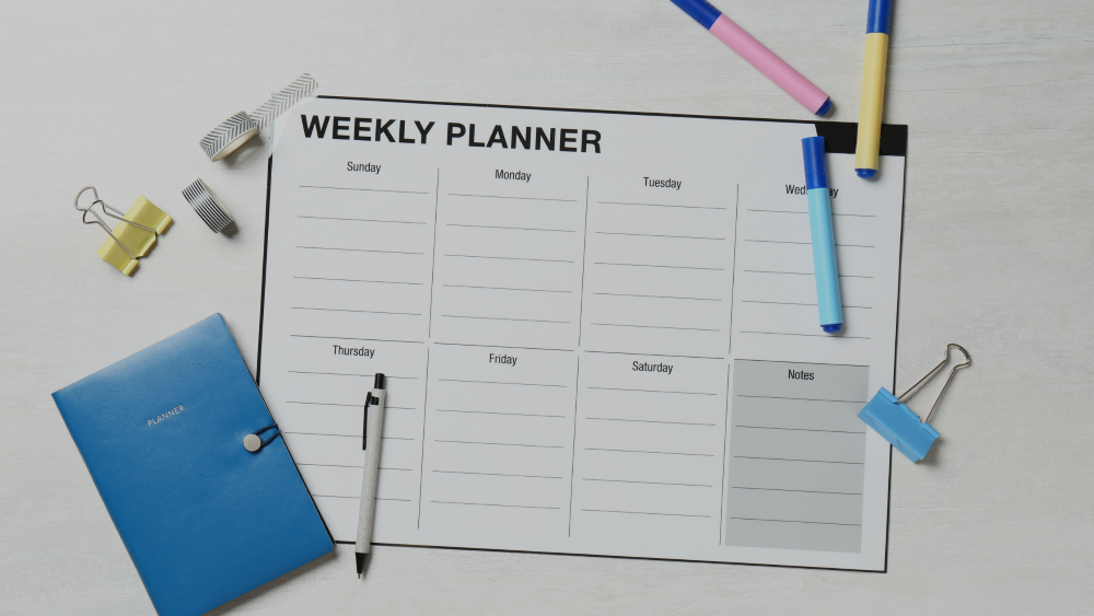Weekly planner calendar with colourful pens and office equipment