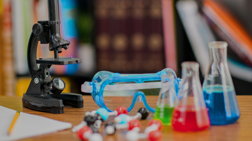 A science classroom with a microscope, googles and colorful liquids in glass flasks