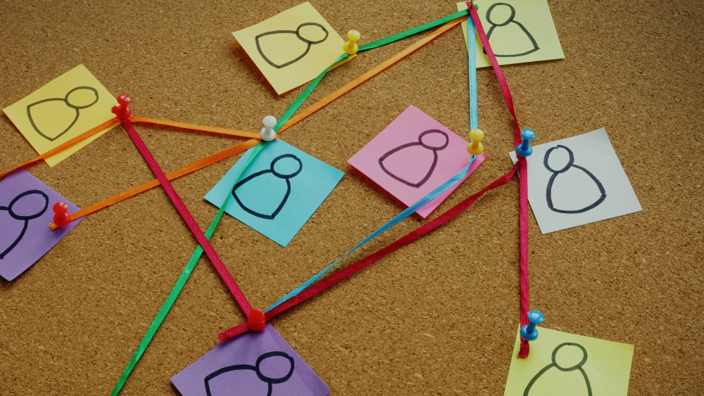 A pin board with graphics of people all connected via ribbons