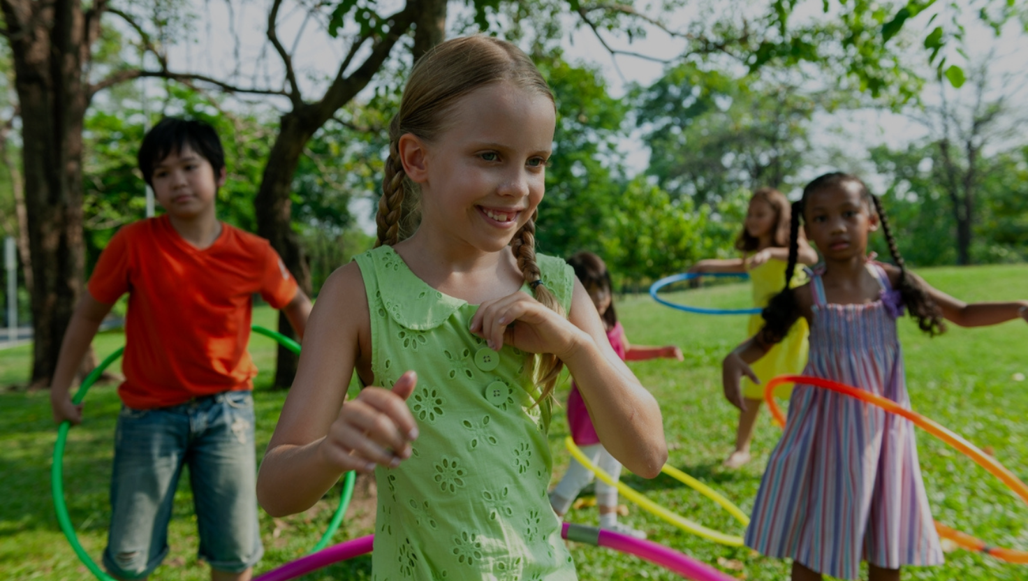young children exercising with hoops outside