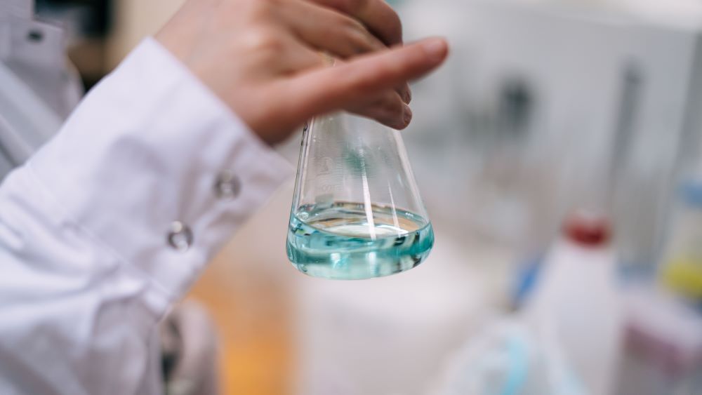 Teen holding a glass science beaker at school.